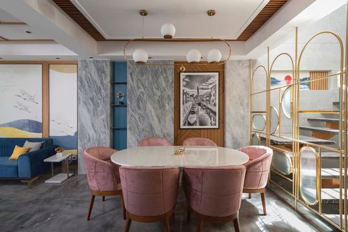 Dining room with oval marble table, pink velvet chairs and gold arched partition screen