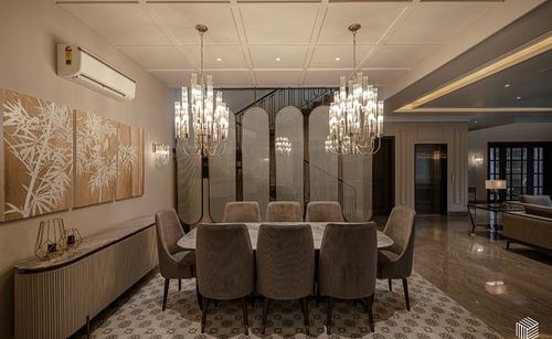 Formal dining room with oval marble table, twin chandeliers, and spiral staircase behind screens