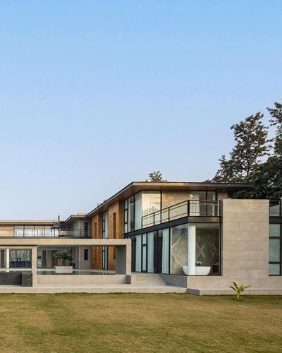 Contemporary two-storey stone and wood residence with pool, cantilevered balcony, and lawn at dusk