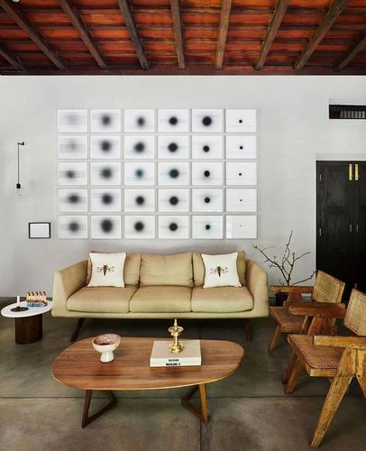 Living room with beige sofa, cane chairs, wood coffee table under exposed wooden roof, art grid on wall