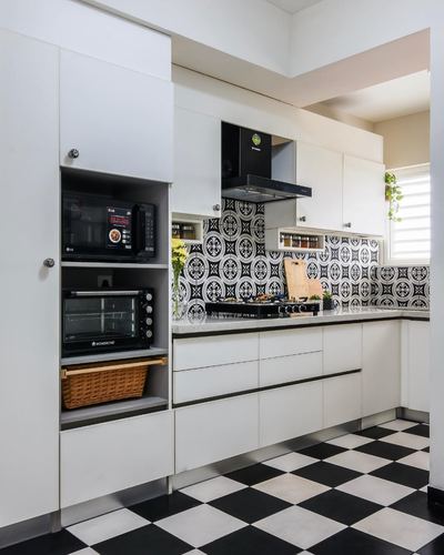 White L-shaped kitchen with black-and-white patterned backsplash and checkerboard floor