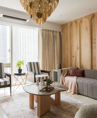 Living room with arched oak panelling, brass leaf chandelier, and marble coffee table