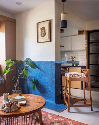 Living room with blue textured half-wall opening into kitchen counter, framed art, and wooden coffee table