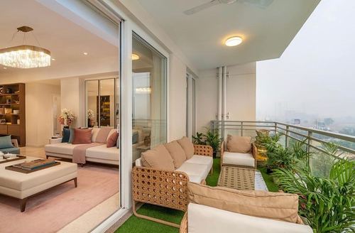Balcony seating in cane furniture on artificial turf overlooking a hazy city skyline.