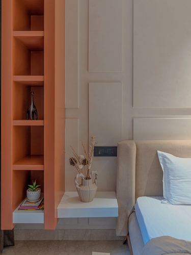Orange open shelving beside upholstered bed with floating nightstand and ceramic vase