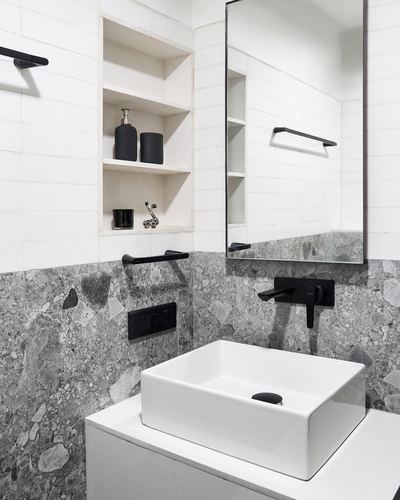 Minimalist bathroom with white tile, grey stone-look wall, black fixtures, and rectangular vessel sink