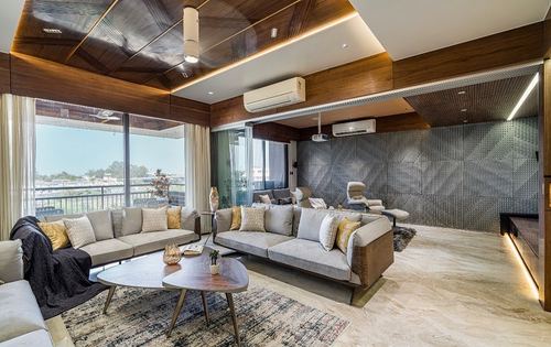 Living room with wood-panelled ceiling, grey sofas, textured metal wall and balcony view