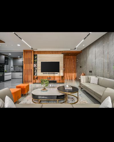 Living room with wood-clad TV wall, stone accent, oval nesting tables and orange ottomans