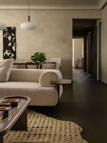 Beige boucle sofa in living room with cocoon pendant lights and view into dining area and hallway
