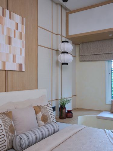 Bedroom corner with wood-panelled wall, stacked paper lantern pendants, and textured bedding near window