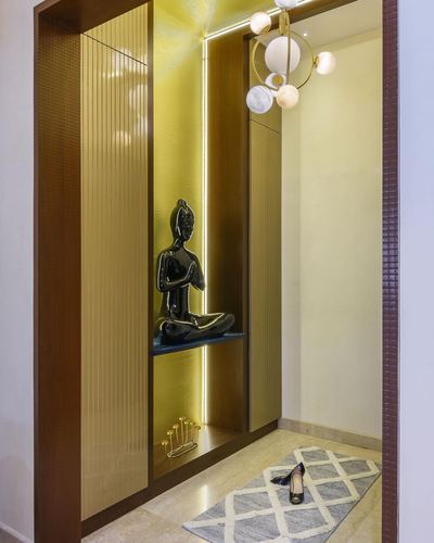Entryway niche with backlit fluted panel and buddha statue, chandelier above patterned rug