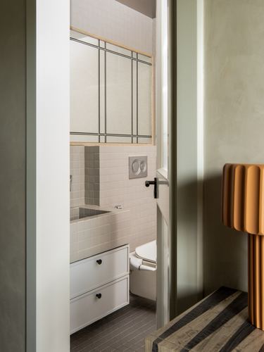 View through doorway into a small tiled bathroom with reeded glass partition and wall-hung basin