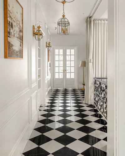 Panelled corridor with diamond marble floor, brass lanterns, and glass french doors