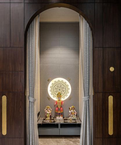 Arched wooden doorway with curtains framing a backlit pooja niche with deity idols