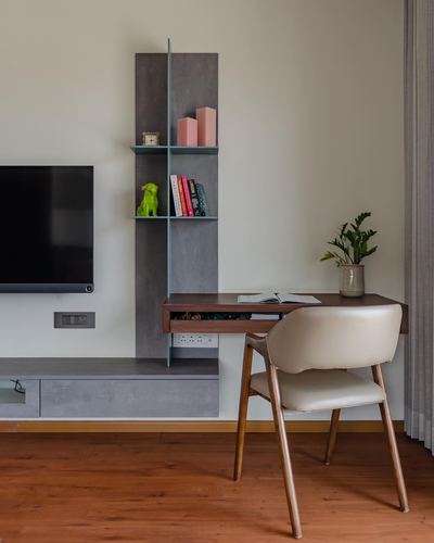 Wall-mounted TV above a grey shelving unit beside a wooden study desk and chair