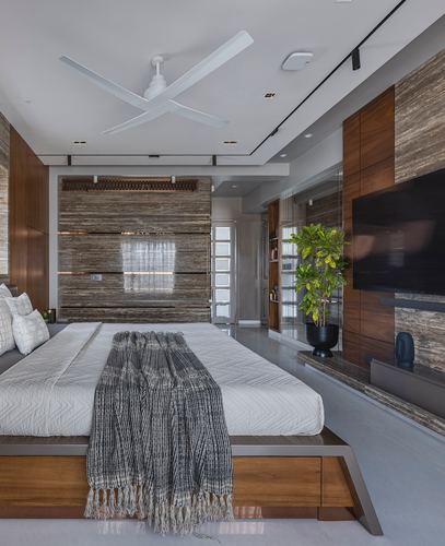 Modern bedroom with stone-clad wall, wooden platform bed, and wall-mounted television