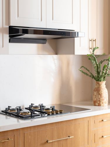 Cream cabinetry kitchen with wood-fronted island, gas cooktop, and vase of eucalyptus