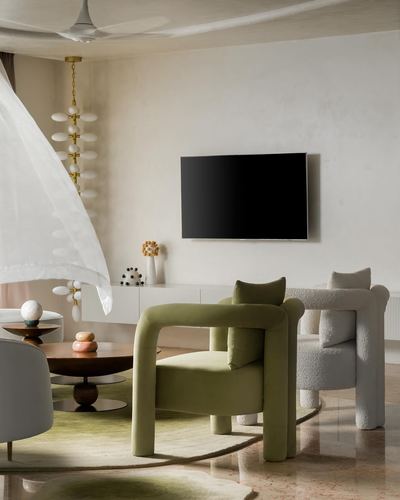 Living room with olive velvet armchair, boucle sofa, wall-mounted tv and sculptural chandelier