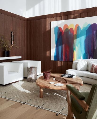 Living room corner with wood paneled walls, boucle sofa, and colorful abstract painting