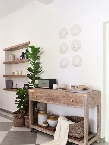 Foyer with wooden console table, woven baskets, fiddle-leaf fig and ceramic face wall art