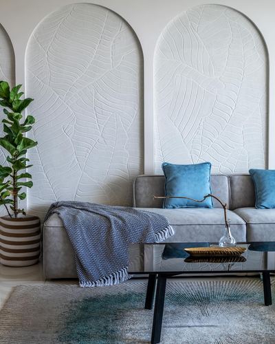 Grey sofa with blue cushions in front of arched leaf-textured plaster wall panels