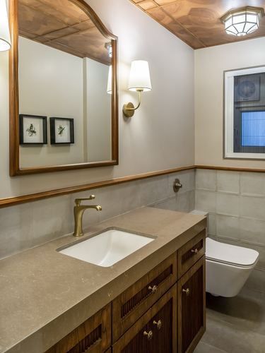 Bathroom vanity with arched wood mirror, brass fittings, fluted cabinetry and stone countertop