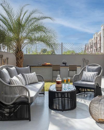 Rooftop terrace lounge with rope-weave sofas, round table and outdoor bar under a palm tree