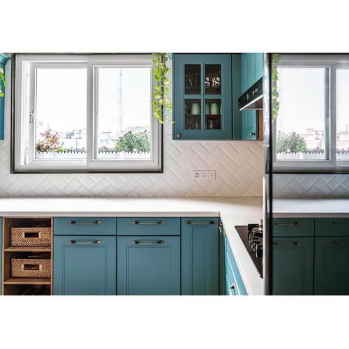Teal kitchen cabinets with herringbone tile backsplash and large window, mirrored composition