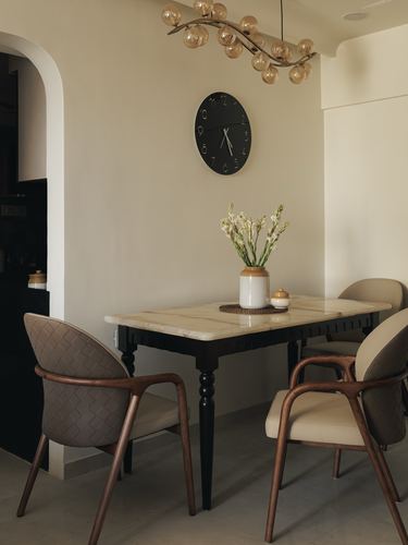 Dining nook with marble-top black table, woven leather chairs, wall clock and globe chandelier