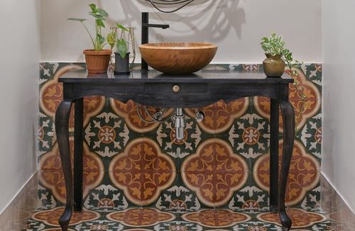Black console vanity with carved wood bowl sink against patterned cement tile wall