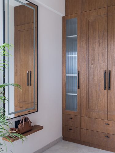 Wooden wardrobe with fluted glass panel and mirror above a small ledge shelf in a foyer