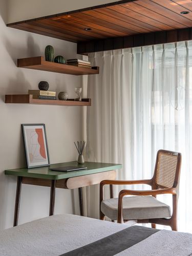 Bedroom corner with cane armchair, green desk, wood shelves and sheer curtained window