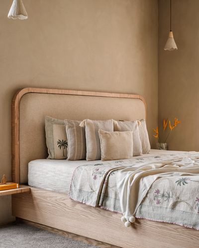 Beige bedroom with rounded wooden headboard, linen pillows, pendant lights and a floating nightstand