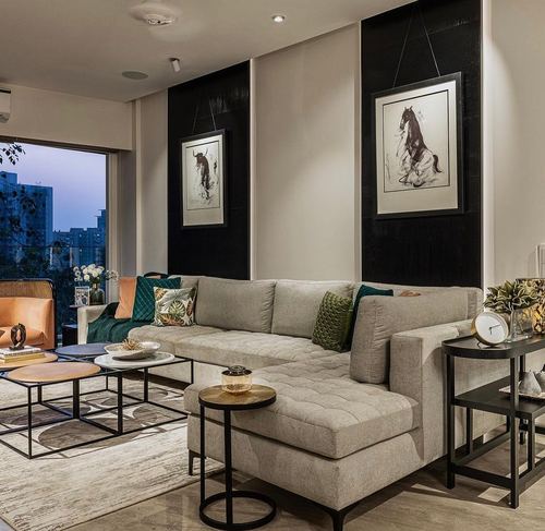Neutral sectional sofa living room with black panel walls and hanging horse and bull sketches at dusk