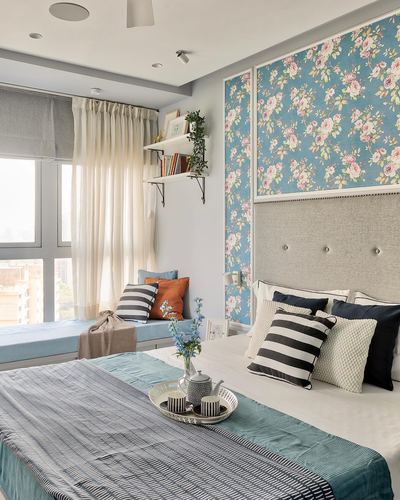 Bedroom with blue floral wallpaper headboard wall and window seat, Mumbai home