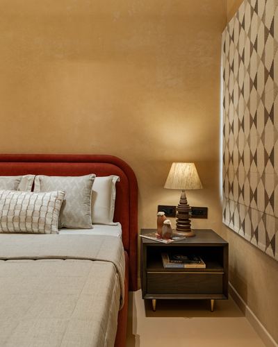 Bedroom corner with rounded terracotta headboard, dark wood nightstand and patterned window blind
