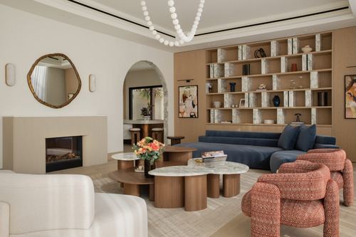 Living room with navy sofa, terracotta chairs, round mirror, ribbed fireplace, and open wood shelving.