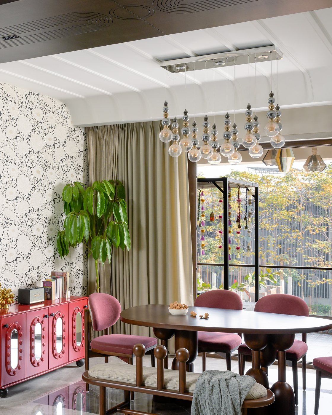 Dining room with pink chairs, oval wood table, and cascading bubble chandelier