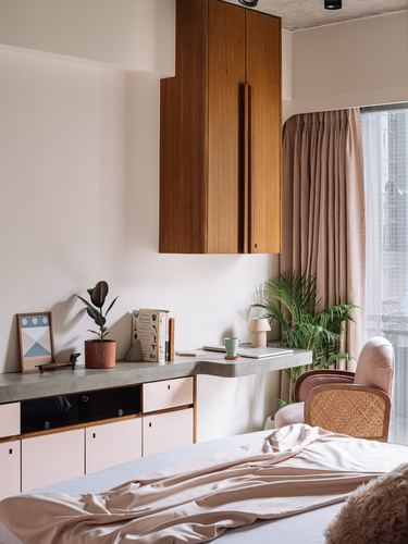 Bedroom corner with wood cabinet, concrete desk, blush cabinetry and cane chair by window