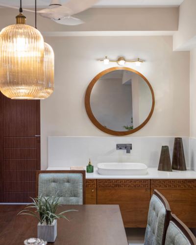 Round wood-framed mirror above white vessel sink vanity with fluted lantern pendants