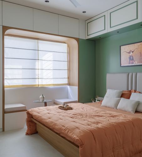 Bedroom with terracotta bedding, green wall, and arched wood window seat nook