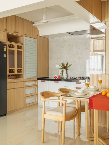 Wood-panelled kitchen with white cabinetry opens to a glass dining table set for a meal