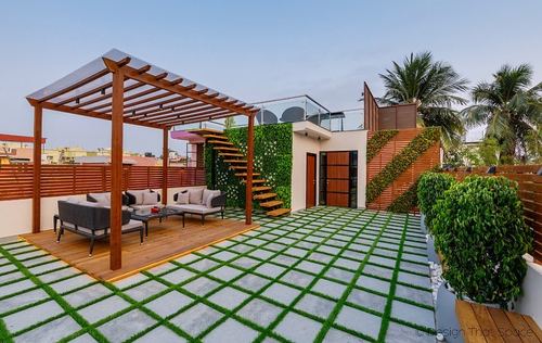 Rooftop terrace with wooden pergola, seating, staircase and vertical garden wall in Kolkata