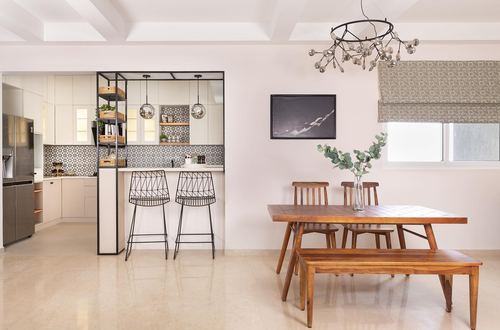 Open dining and kitchen area with wooden table, wire barstools, and patterned tile backsplash