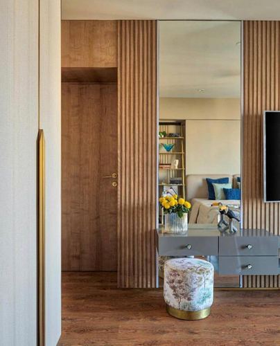 Foyer with fluted wood panelling, full-length mirror, console table and floral stool