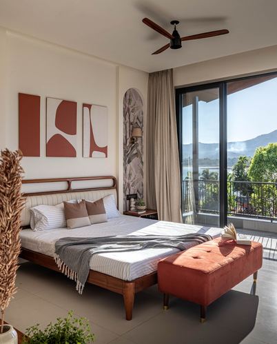 Bedroom with terracotta bench and cane bed frame facing a lake-view balcony
