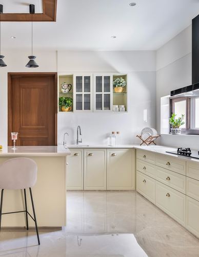 Cream L-shaped kitchen with marble floor, walnut door, and glass display cabinets