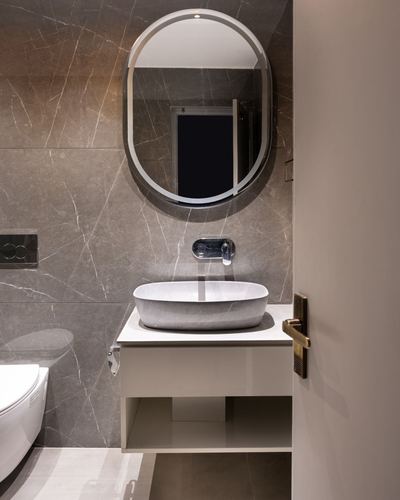 Modern bathroom with backlit oval mirror, stone vessel sink, and floating vanity