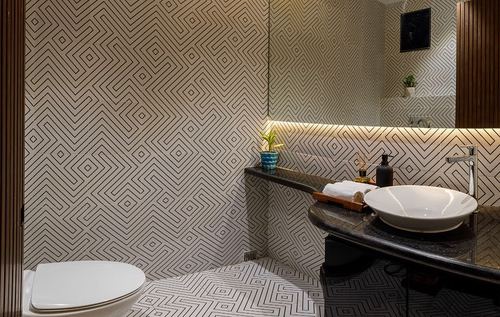 Powder room with geometric patterned tile walls, dark stone vanity and vessel sink under cove lighting