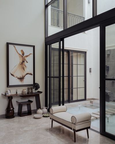 Foyer with tall painting, dark wood console, and bench beside floor-to-ceiling black-framed glass wall